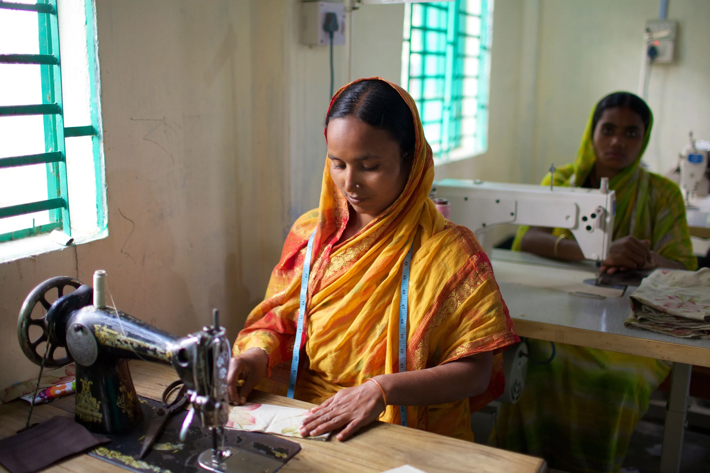 Illustrative stock photograph: garment makers working at sewing machines in Bangladesh.